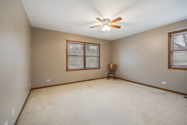 an empty room with windows and ceiling fan