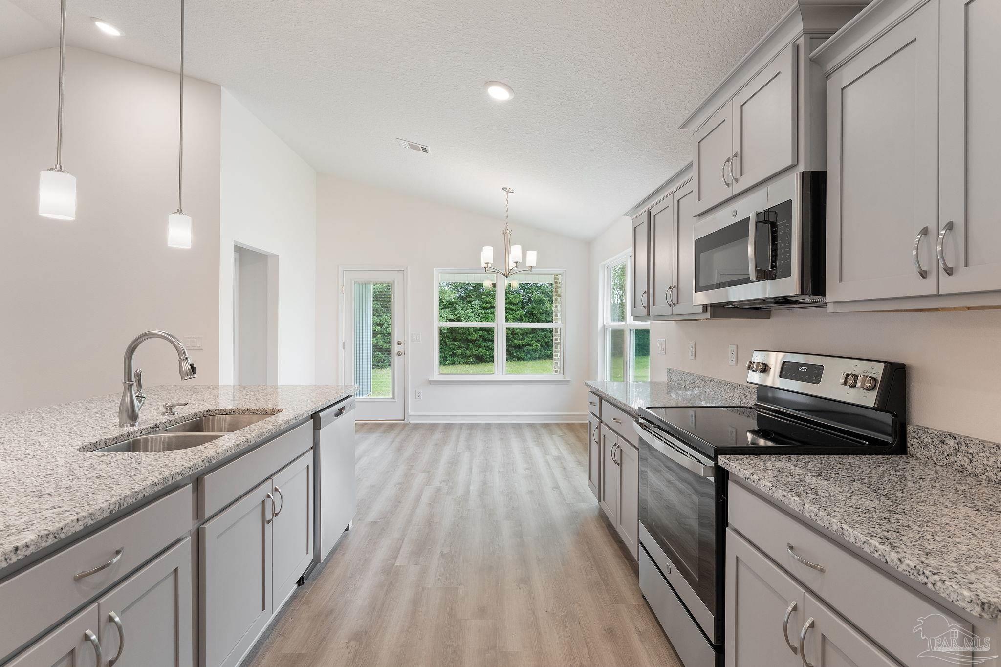 4930 East Spencer Field Road Pace, FL 32571 - Photo 5 of 28 a kitchen with granite countertop stainless steel appliances a stove sink and cabinets