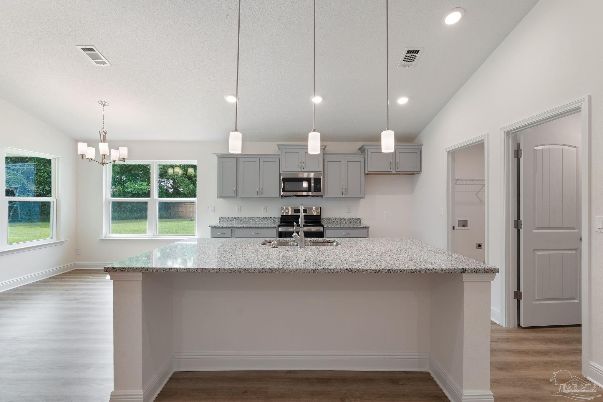 4930 East Spencer Field Road Pace, FL 32571 - Photo 6 of 28 a large kitchen with kitchen island a large counter top space a sink stainless steel appliances and cabinets