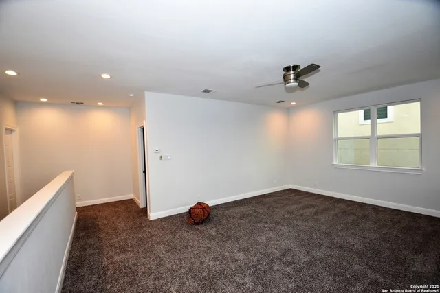 an empty room with windows and fan