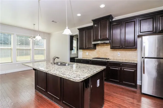 a kitchen with kitchen island granite countertop wooden cabinets and refrigerator