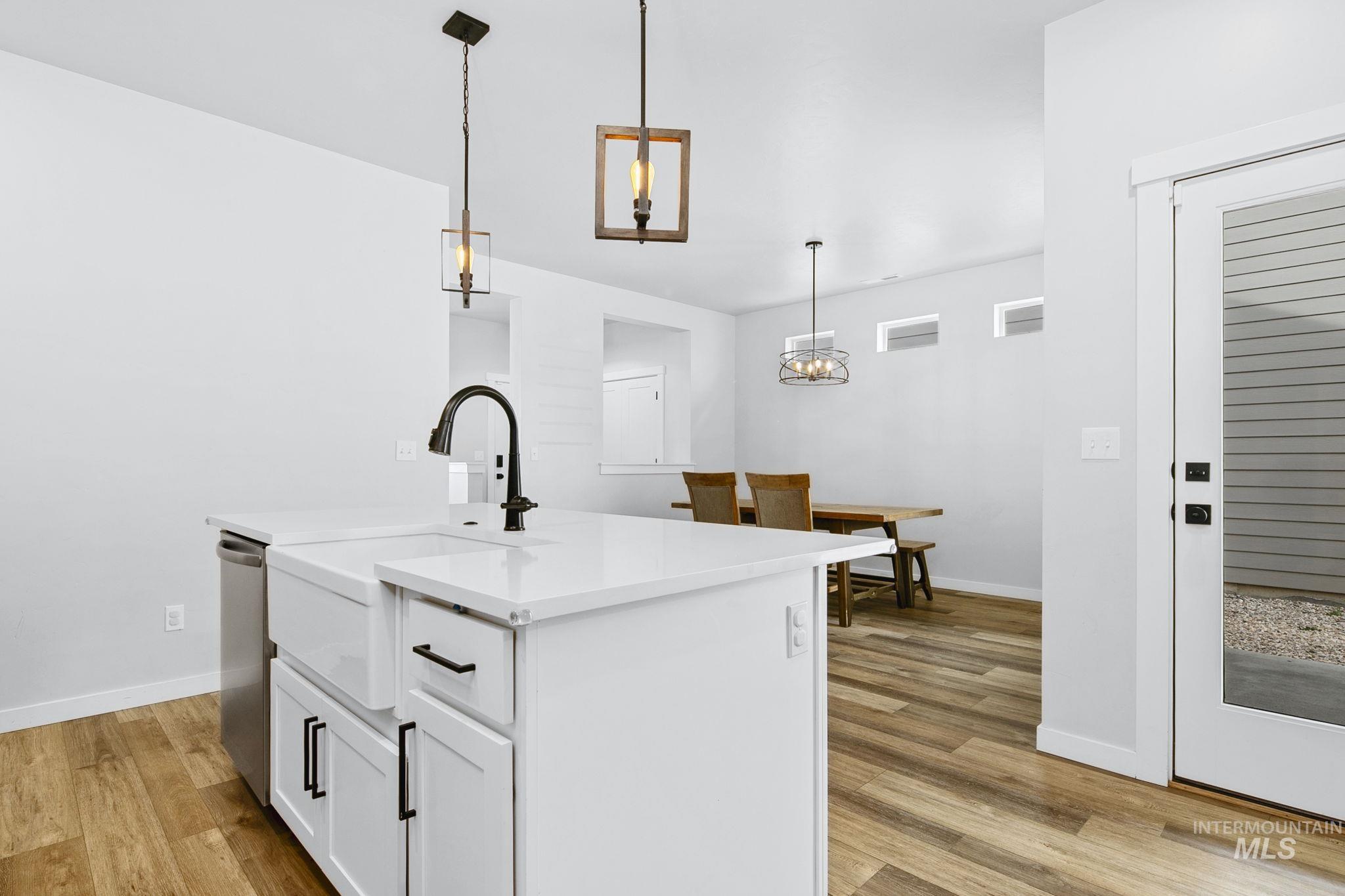298 South Fritts Avenue Meridian, ID 83642 - Photo 12 of 32 Kitchen featuring white cabinetry, light wood-style flooring, hanging light fixtures, a kitchen island with sink, and light stone counters