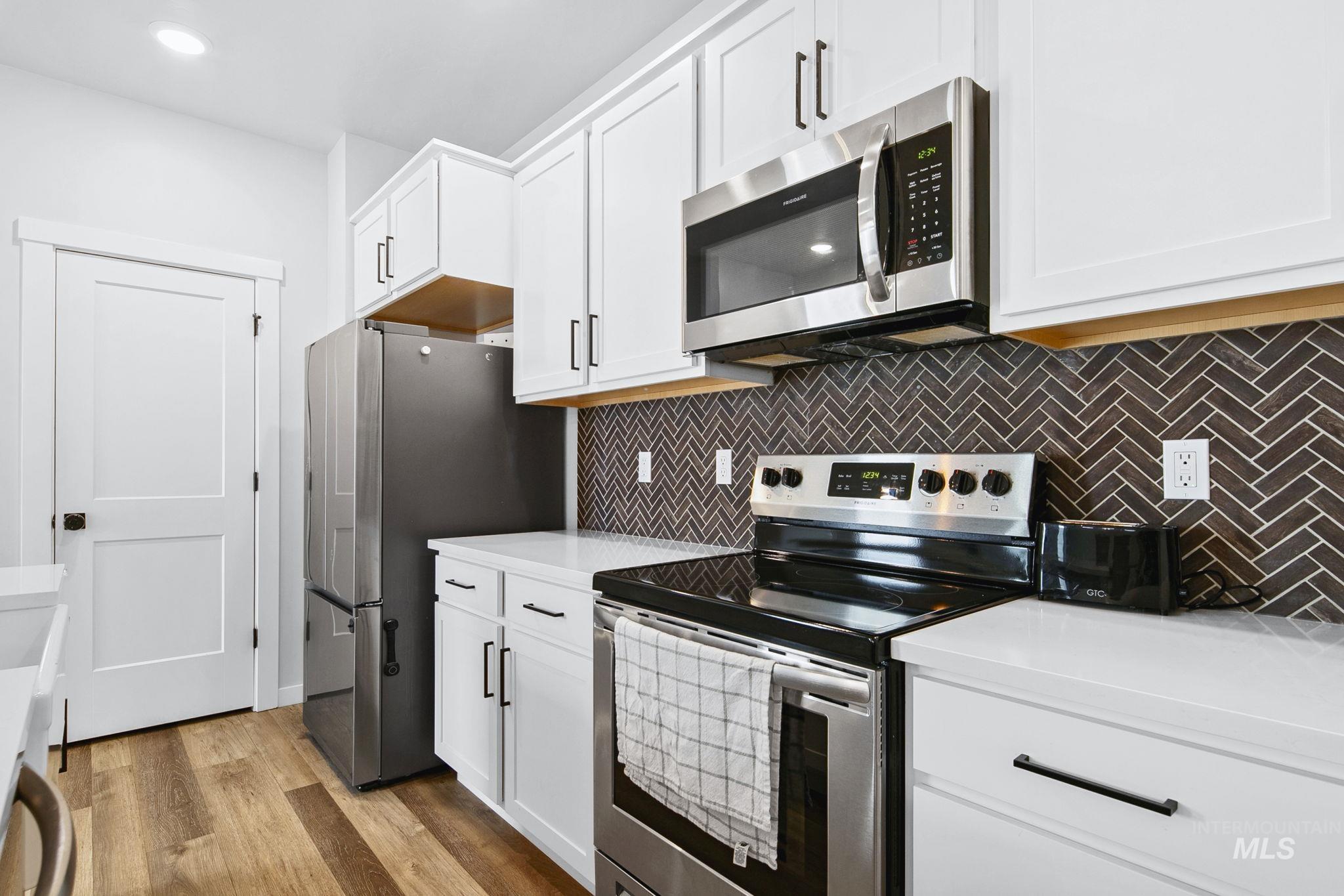 298 South Fritts Avenue Meridian, ID 83642 - Photo 13 of 32 Kitchen with stainless steel appliances, white cabinets, light wood-type flooring, backsplash, and recessed lighting