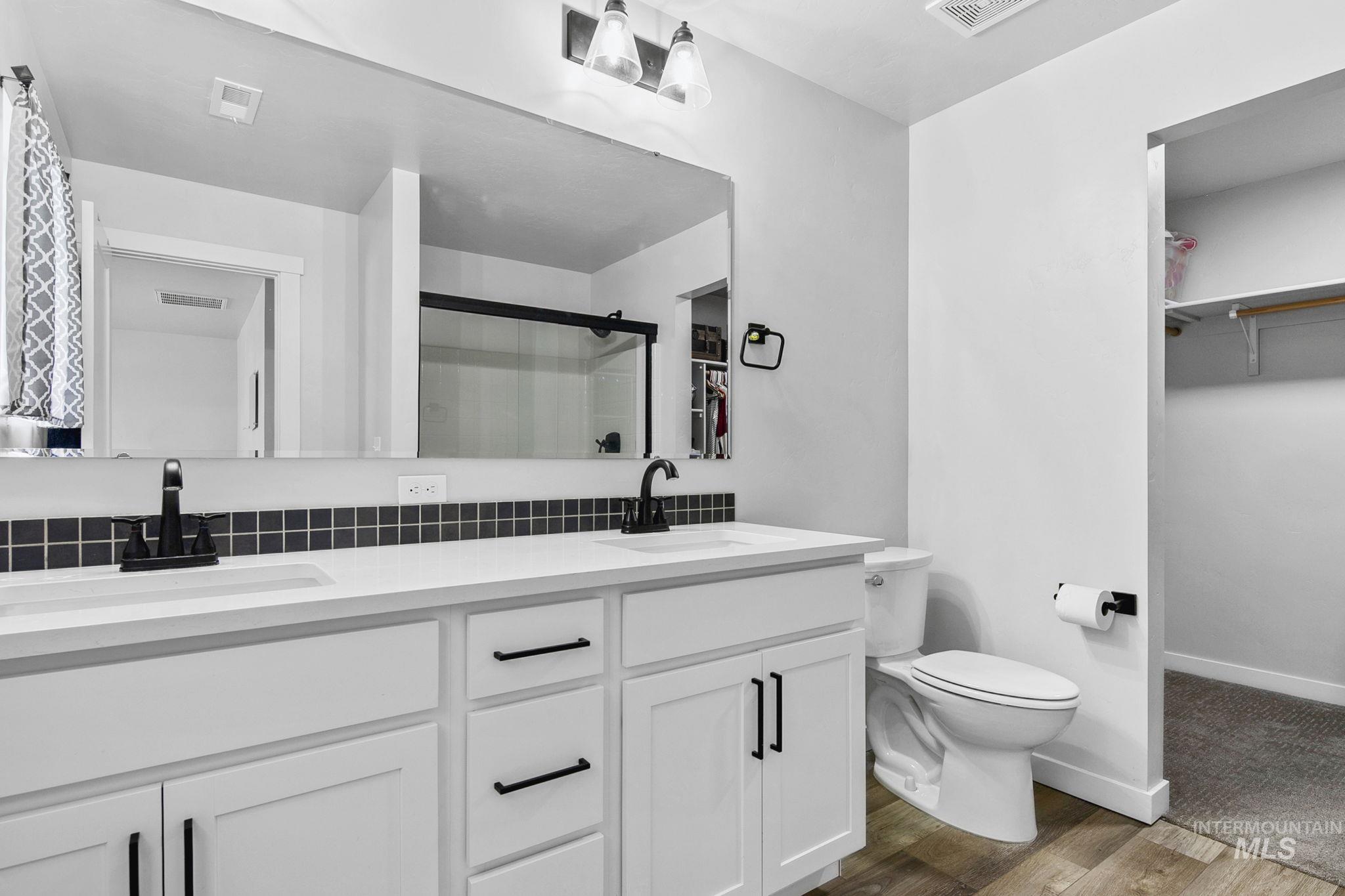 298 South Fritts Avenue Meridian, ID 83642 - Photo 18 of 32 Full bathroom with a spacious closet, double vanity, dark wood-style flooring, and a shower stall