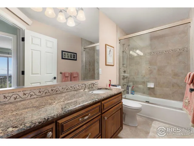 a bathroom with a granite countertop sink a toilet a mirror and shower