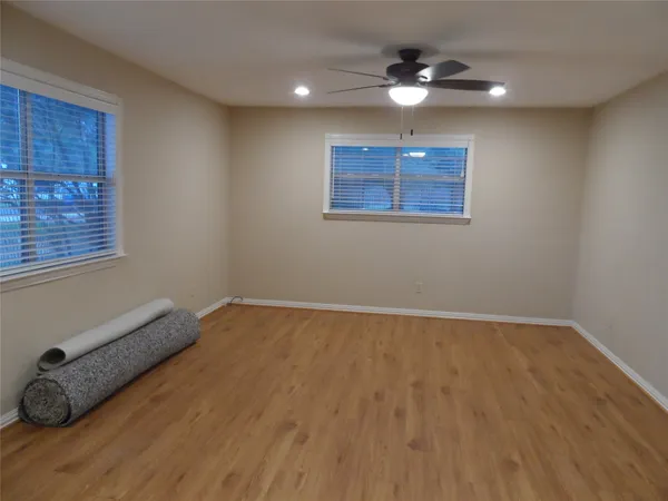 an empty room with wooden floor and windows