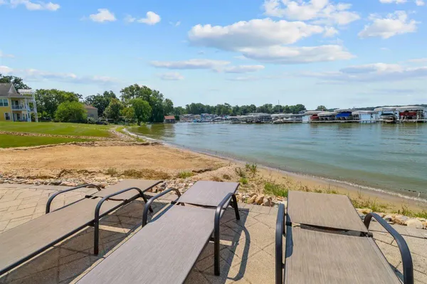 a kitchen with stainless steel appliances kitchen island granite countertop a stove top oven a sink a dining table and chairs with wooden floor