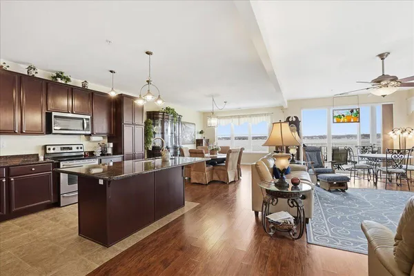 a view of a dining room with furniture one side kitchen view and wooden floor