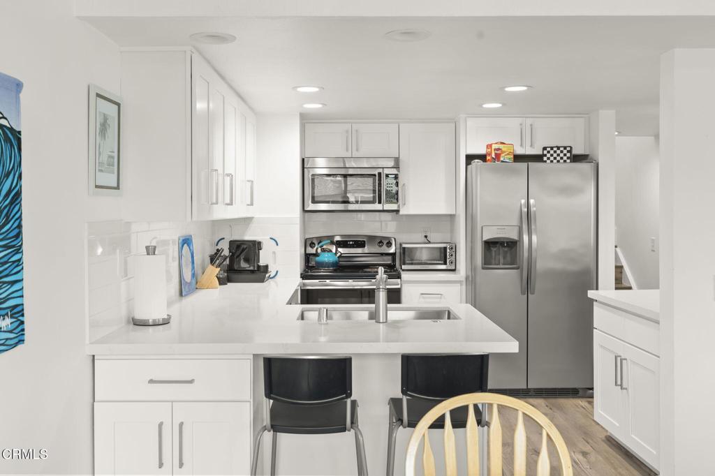 3464 Sunset Lane Oxnard, CA 93035 - Photo 19 of 46 a kitchen with stainless steel appliances a sink a stove a refrigerator cabinets and chairs