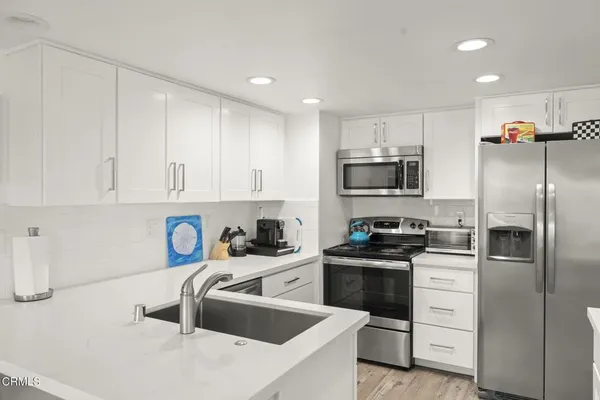 a kitchen with white cabinets and stainless steel appliances