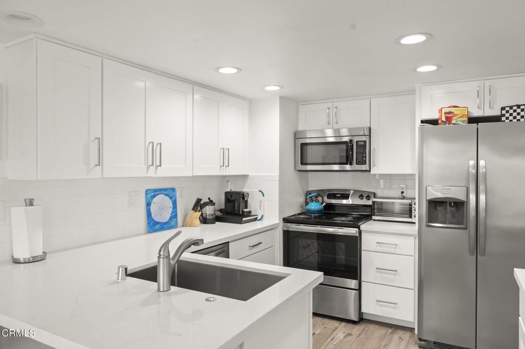 3464 Sunset Lane Oxnard, CA 93035 - Photo 20 of 46 a kitchen with white cabinets and stainless steel appliances
