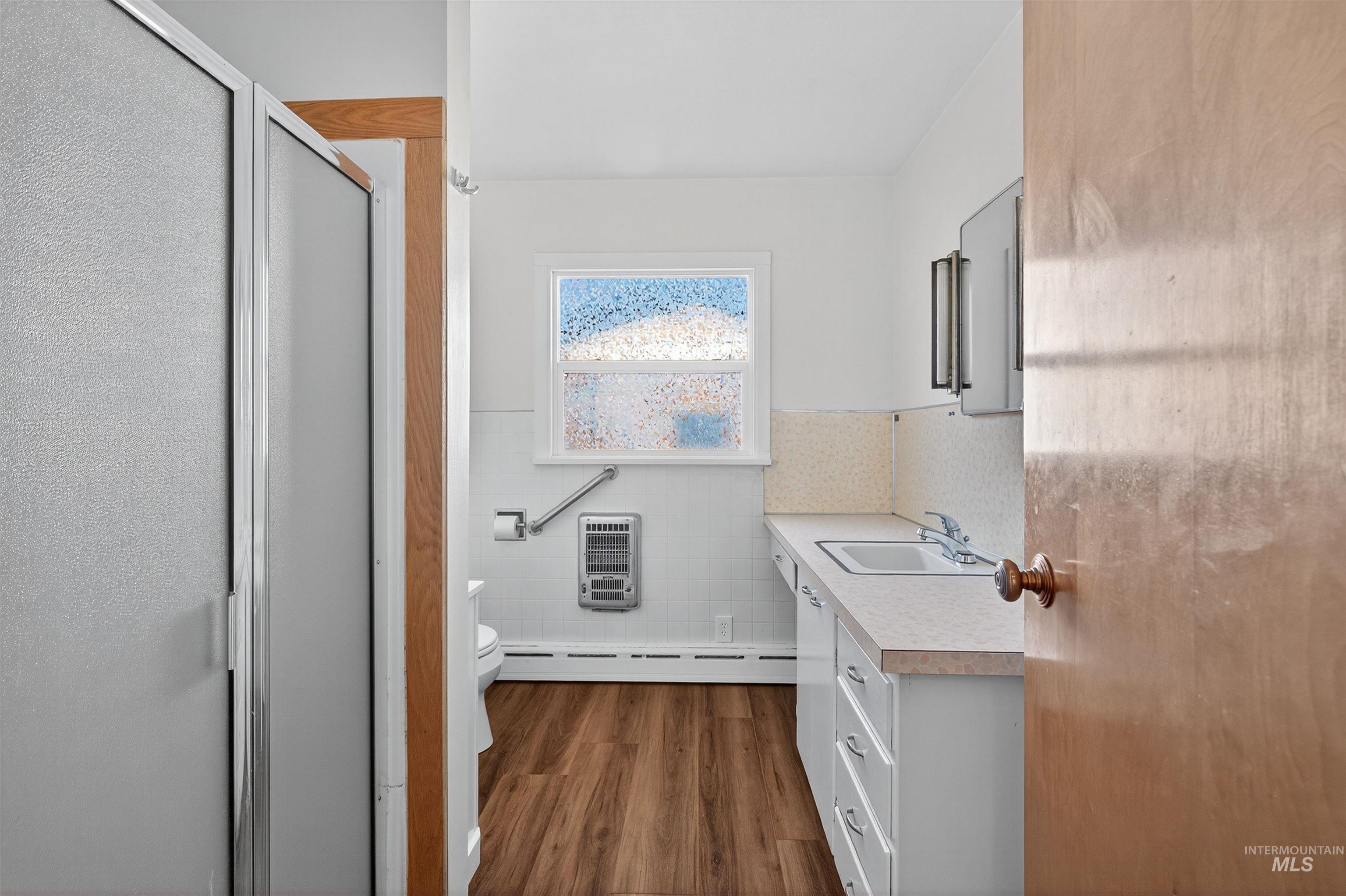 164 State Street Juliaetta, ID 83535 - Photo 11 of 37 Full bath with vanity, tile walls, a shower stall, dark wood-type flooring, and wainscoting