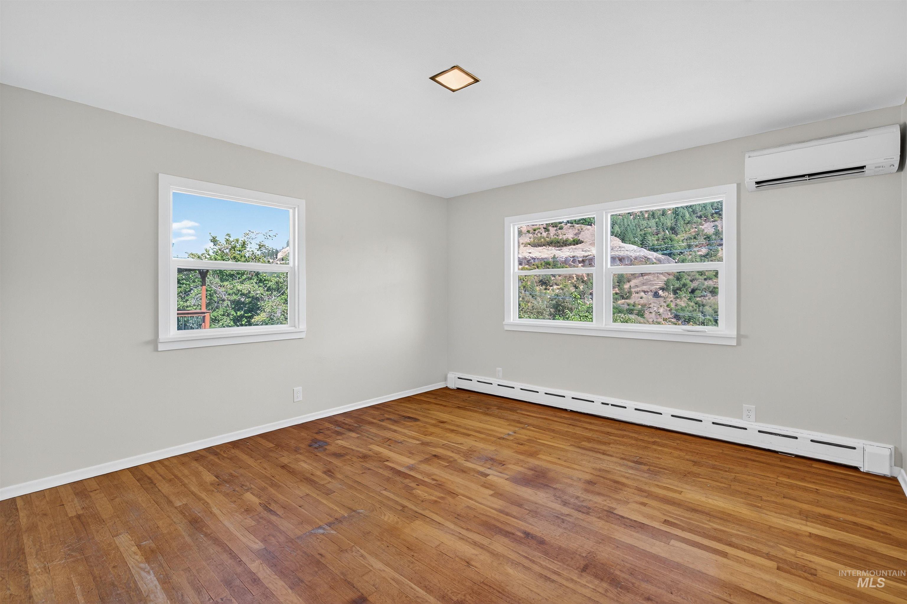 164 State Street Juliaetta, ID 83535 - Photo 12 of 37 Unfurnished room featuring a baseboard heating unit, a wall mounted AC, and hardwood / wood-style flooring