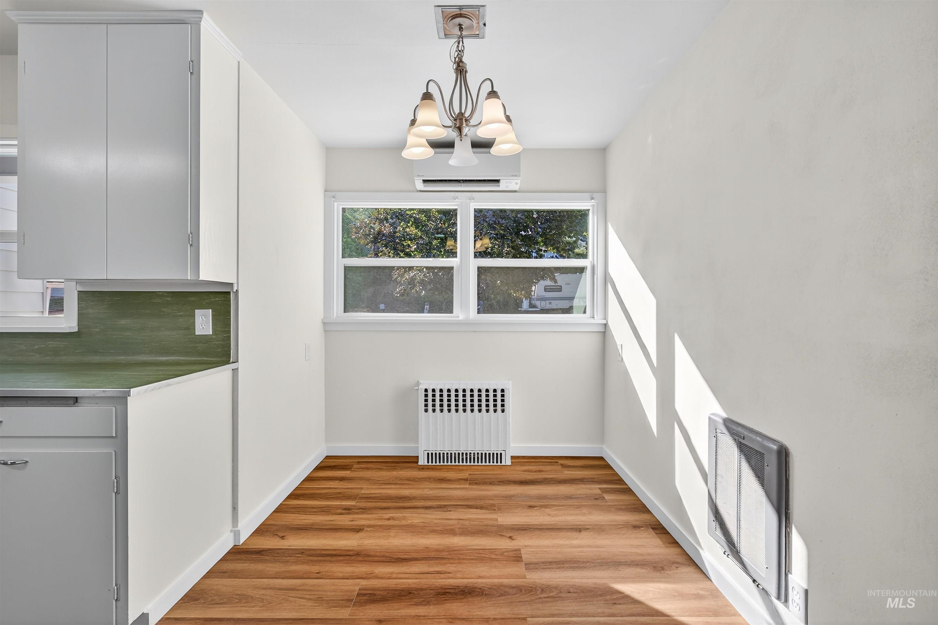 164 State Street Juliaetta, ID 83535 - Photo 17 of 37 Unfurnished dining area with light wood finished floors, radiator, an AC wall unit, a chandelier, and heating unit