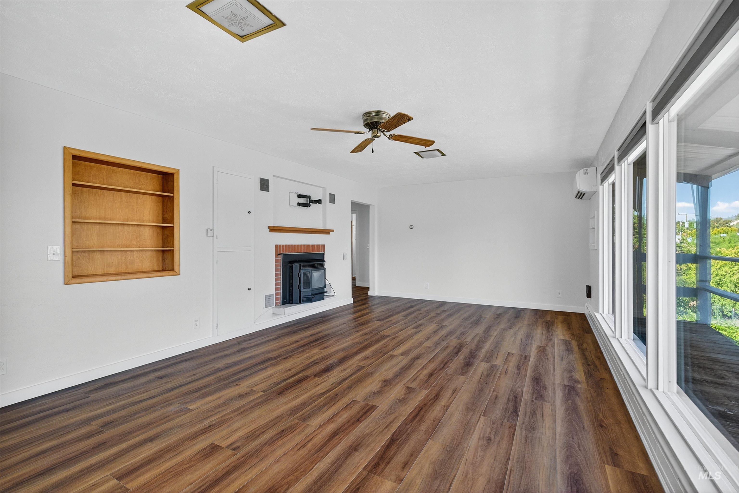 164 State Street Juliaetta, ID 83535 - Photo 19 of 37 Unfurnished living room featuring built in shelves, dark wood-style flooring, a fireplace, ceiling fan, and a baseboard radiator