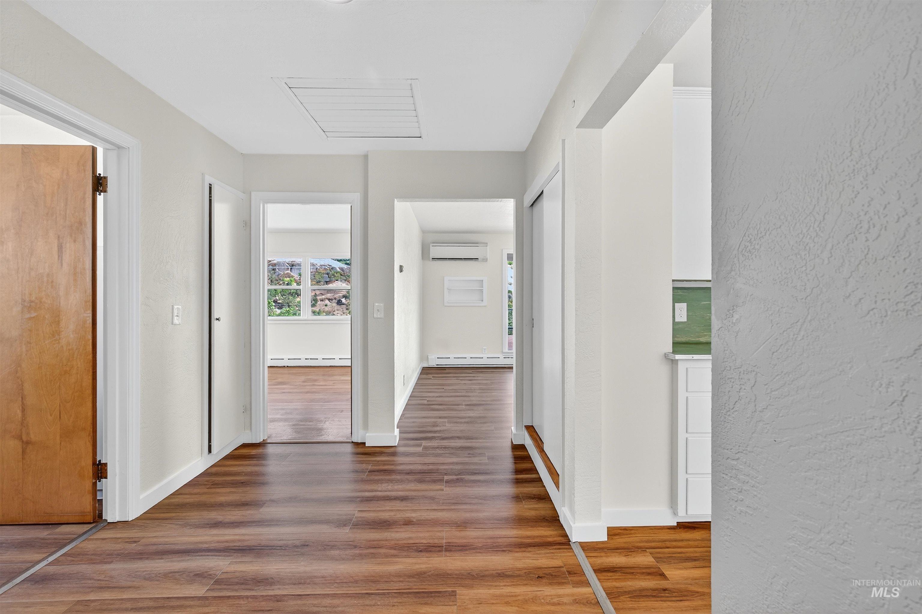 164 State Street Juliaetta, ID 83535 - Photo 8 of 37 Hallway with wood finished floors, a textured wall, a wall mounted AC, and baseboard heating