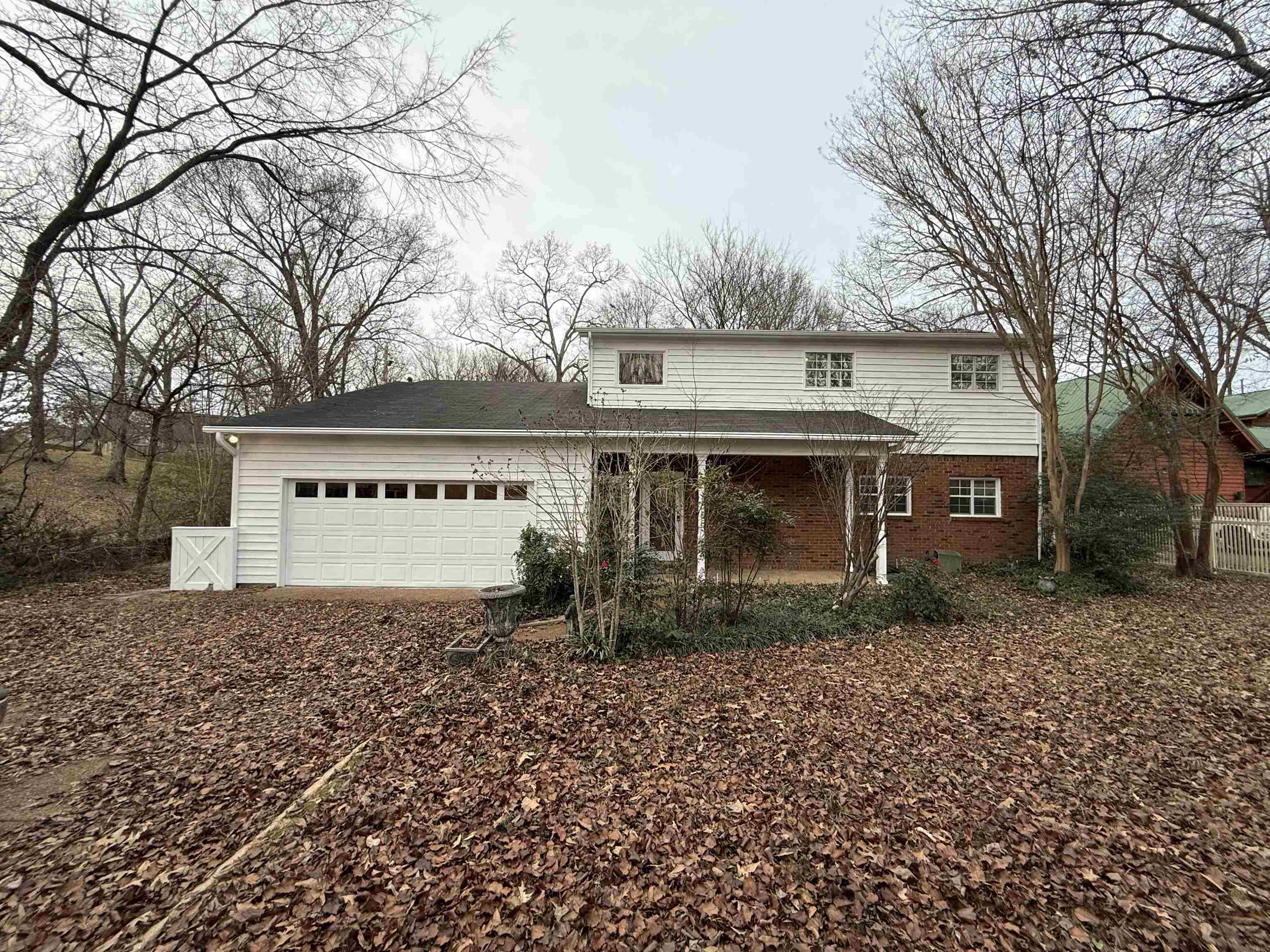 Rear view of property featuring brick siding, a garage, and driveway
