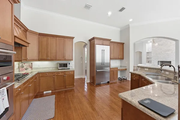 a kitchen with stainless steel appliances kitchen island granite countertop a sink refrigerator and cabinets