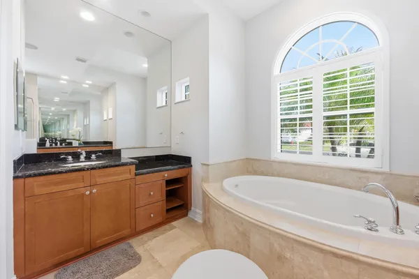 a bathroom with a granite countertop sink a toilet and a tub