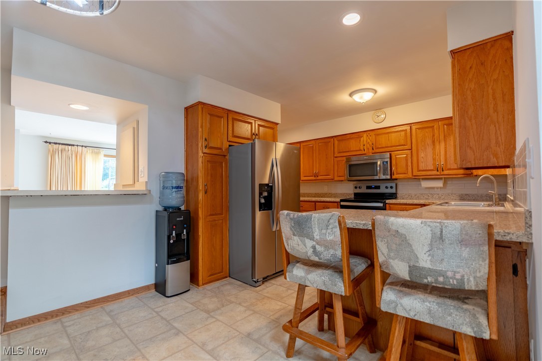 1766 Far View Road Akron, OH 44312 - Photo 7 of 33 Kitchen featuring recessed lighting, stainless steel appliances, a peninsula, brown cabinets, and light countertops