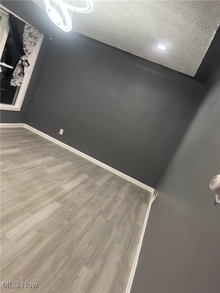 603 Liberty Road Youngstown, OH 44505 - Photo 8 of 42 Spare room featuring wood finished floors, a textured ceiling, and a chandelier