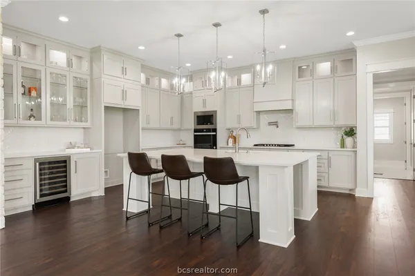 a kitchen with kitchen island granite countertop a stove a sink a refrigerator and a dining table with wooden floor