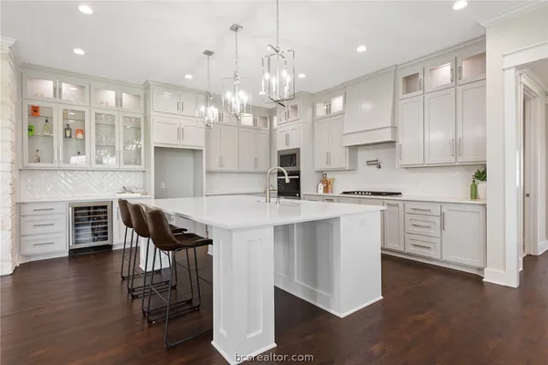 a kitchen with stainless steel appliances kitchen island granite countertop a table chairs in it and white cabinets
