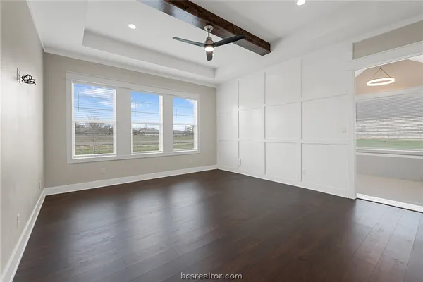 an empty room with wooden floor cabinet and windows