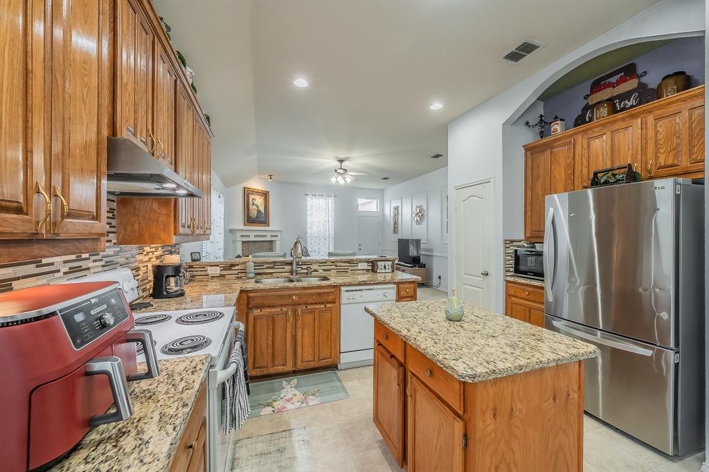 8312 Trinity Vista Trail Hurst, TX 76053 - Photo 13 of 37 Kitchen featuring wood finish cabinetry, white appliances, a peninsula, light stone countertops, and recessed lighting