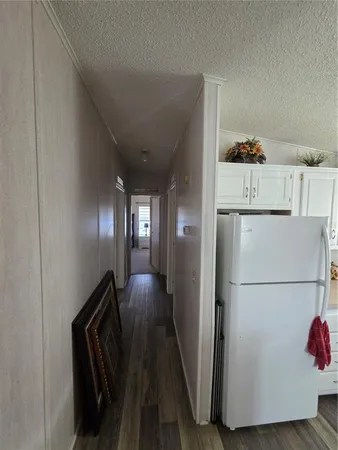 a view of a hallway with stainless steel appliances a refrigerator and a fireplace