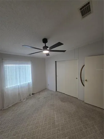 an empty room with windows and fan