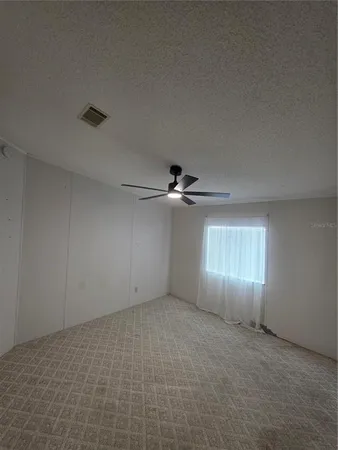 an empty room with windows and chandelier fan