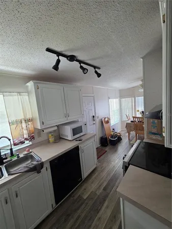 a kitchen that has a sink and a stove with white cabinets