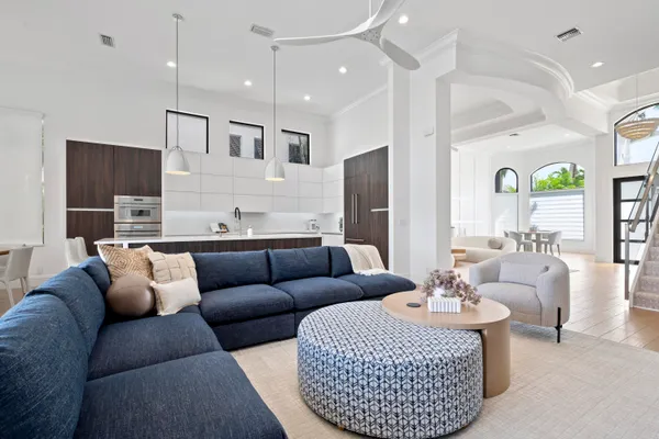 a living room with furniture kitchen view and a chandelier