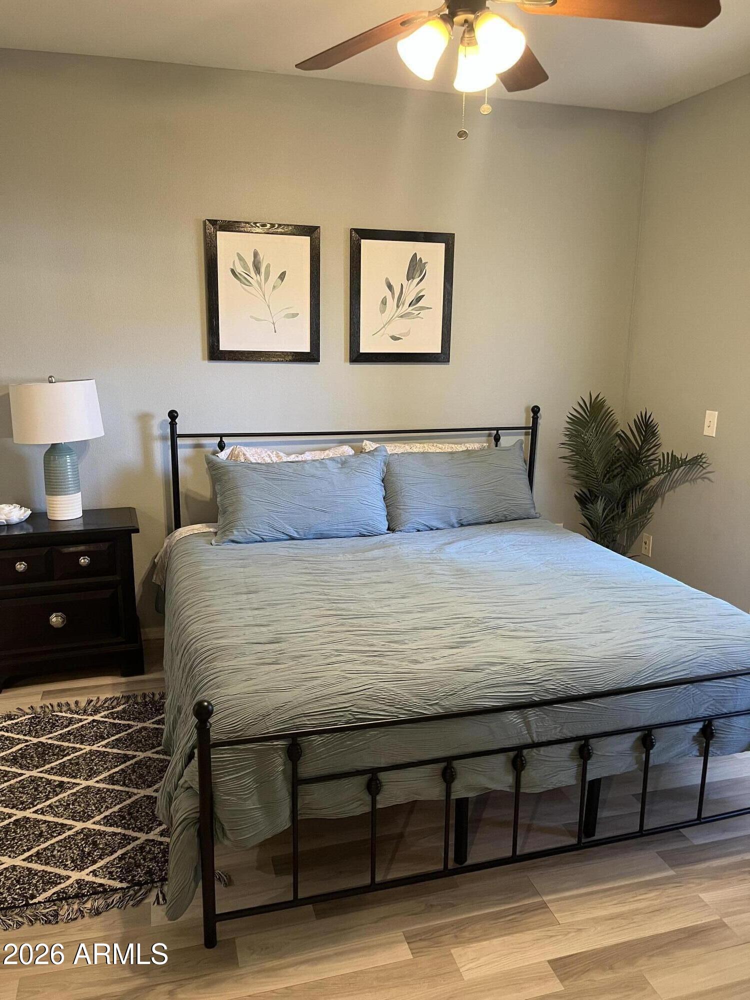 10030 West Indian School Road, Unit 133 Phoenix, AZ 85037 - Photo 3 of 17 a bedroom with a bed and a lamp on dresser