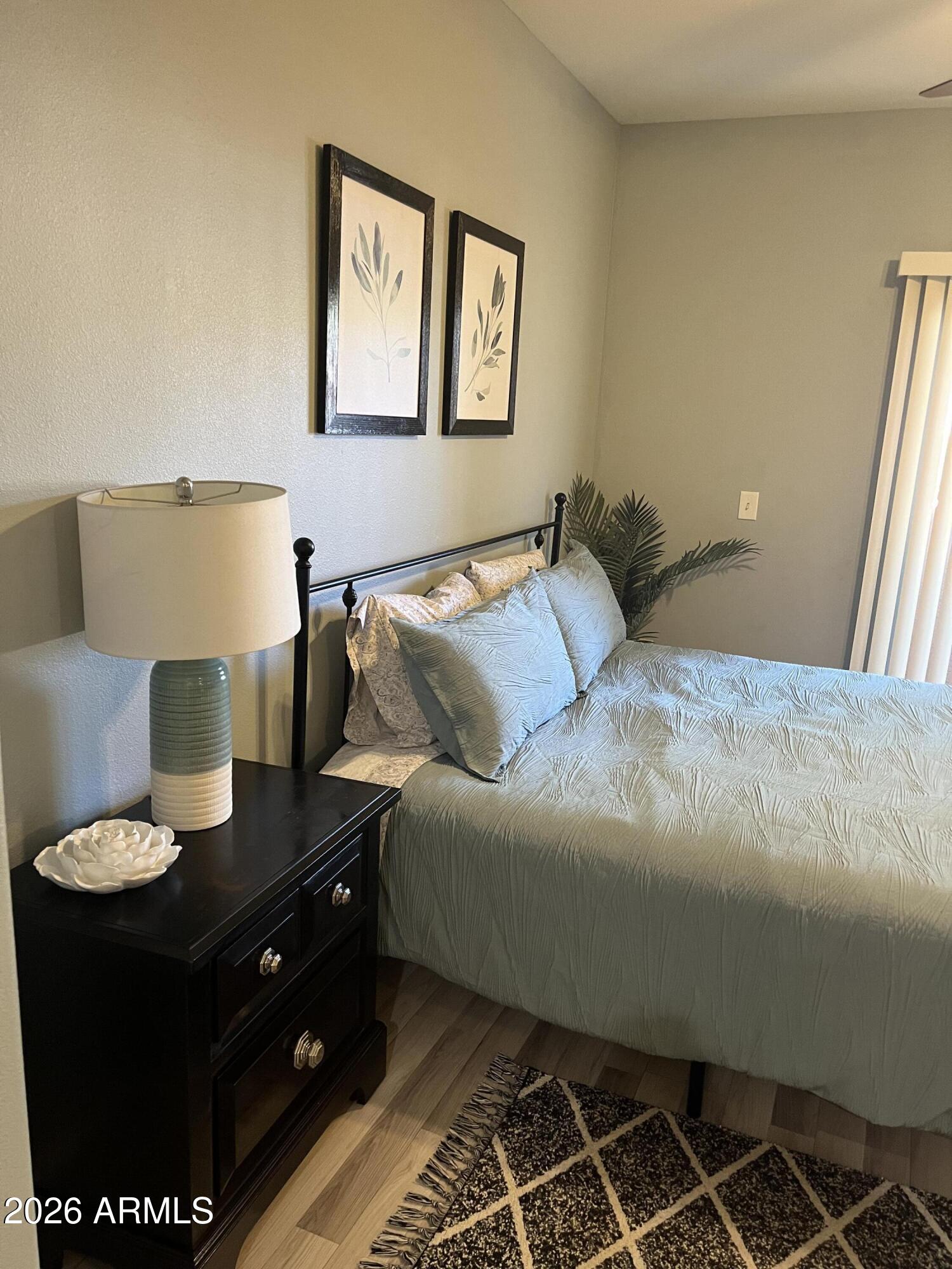 10030 West Indian School Road, Unit 133 Phoenix, AZ 85037 - Photo 4 of 17 a bedroom with a bed and a lamp on dresser