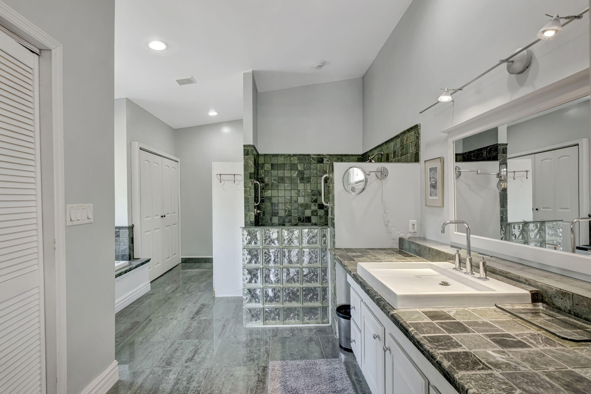 2940 Southeast Treasure Island Road Port St. Lucie, FL 34952 - Photo 34 of 61 a bathroom with a granite countertop sink a large mirror and a shower
