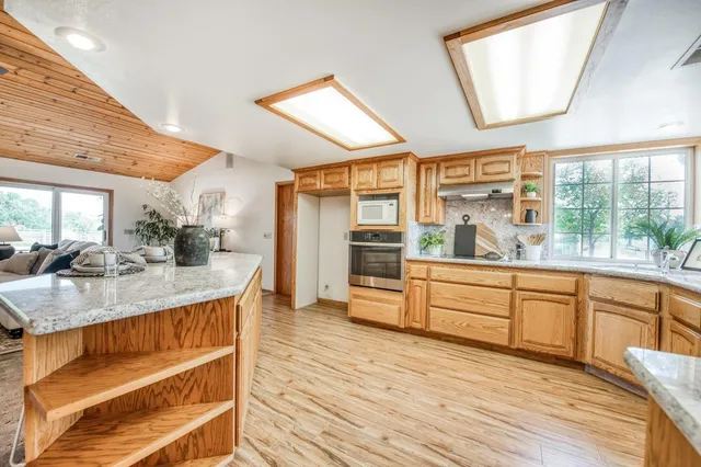 a kitchen with stainless steel appliances granite countertop wooden floors and white cabinets