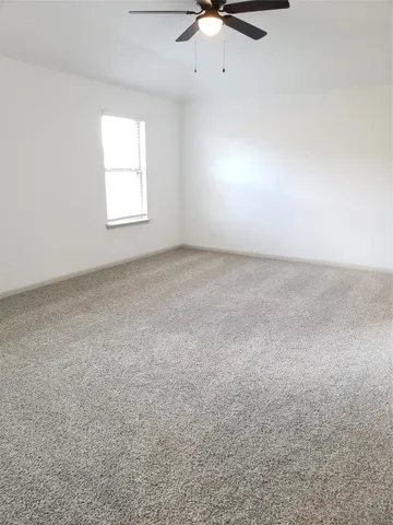 an empty room with a window and a fan