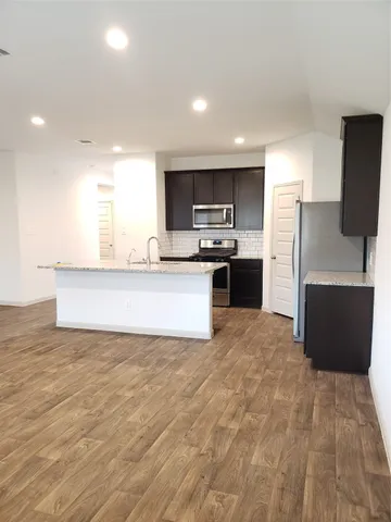 a large kitchen with stainless steel appliances a sink a stove a microwave a counter top space and cabinets