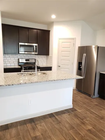 a kitchen with stainless steel appliances granite countertop a refrigerator a stove a sink and a microwave