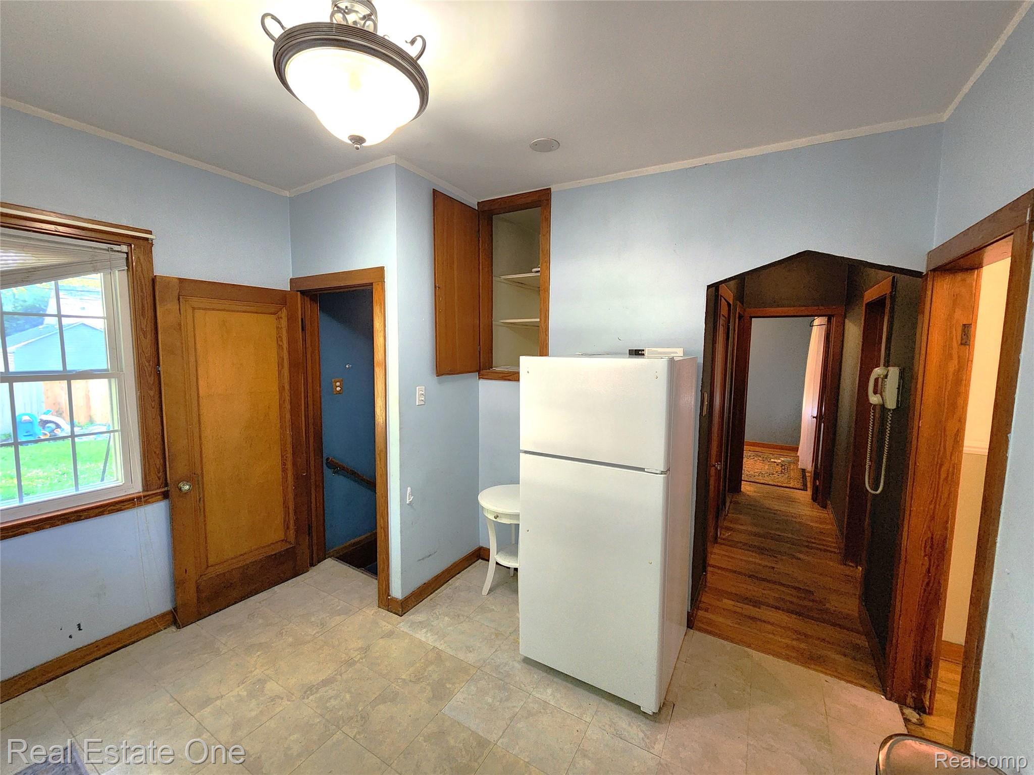 2153 Wiltshire Road Berkley, MI 48072 - Photo 8 of 18 Kitchen area featuring light-toned square floor tiles, a window with wood trim, and a wall-mounted light fixture