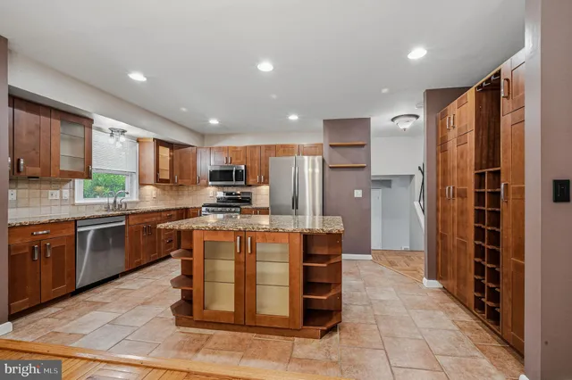 a kitchen with stainless steel appliances granite countertop a refrigerator a sink a stove top oven and a refrigerator