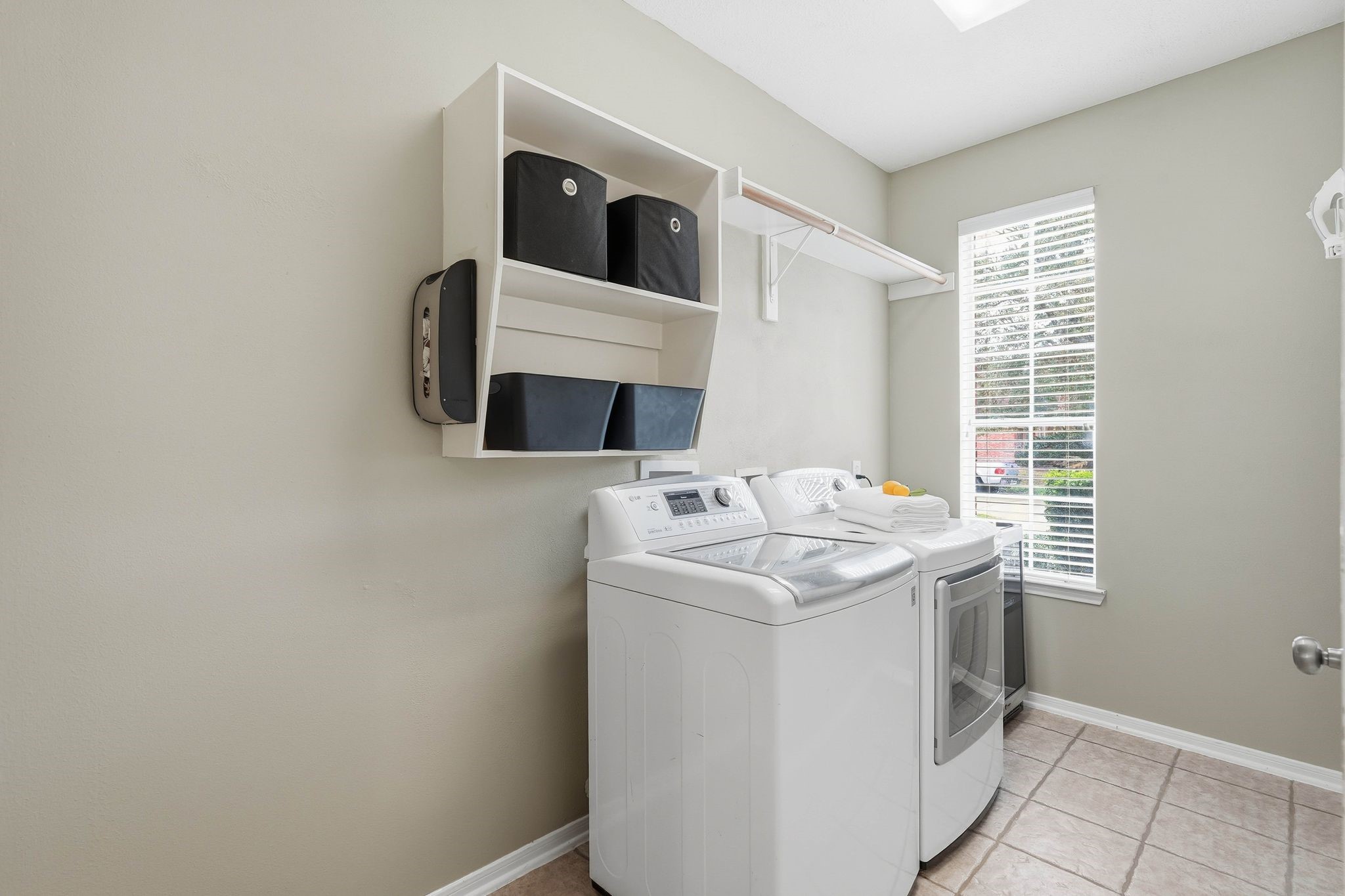 2515 Woodsboro Drive Spring, TX 77388 - Photo 37 of 44 This photo shows a spacious and bright laundry room with shelving for storage. The space is clean and well-organized, with neutral-colored walls and tiled flooring.