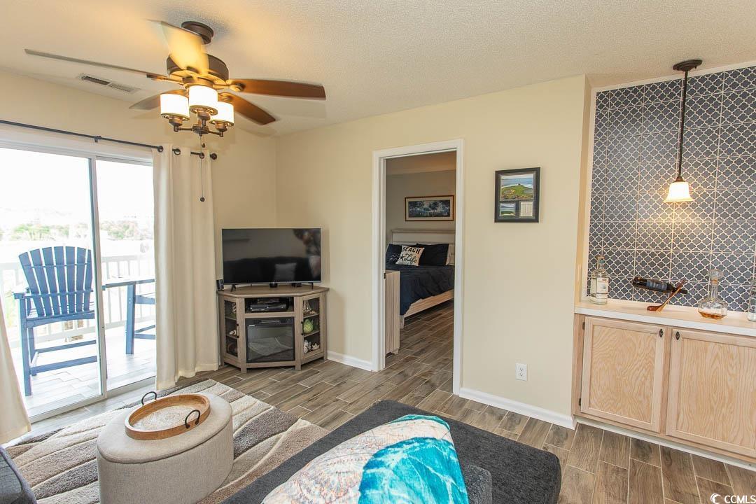 201 Landing Road, Unit D North Myrtle Beach, SC 29582 - Photo 14 of 40 Living area featuring wood tiled floor, wet bar, visible vents, baseboards, and ceiling fan