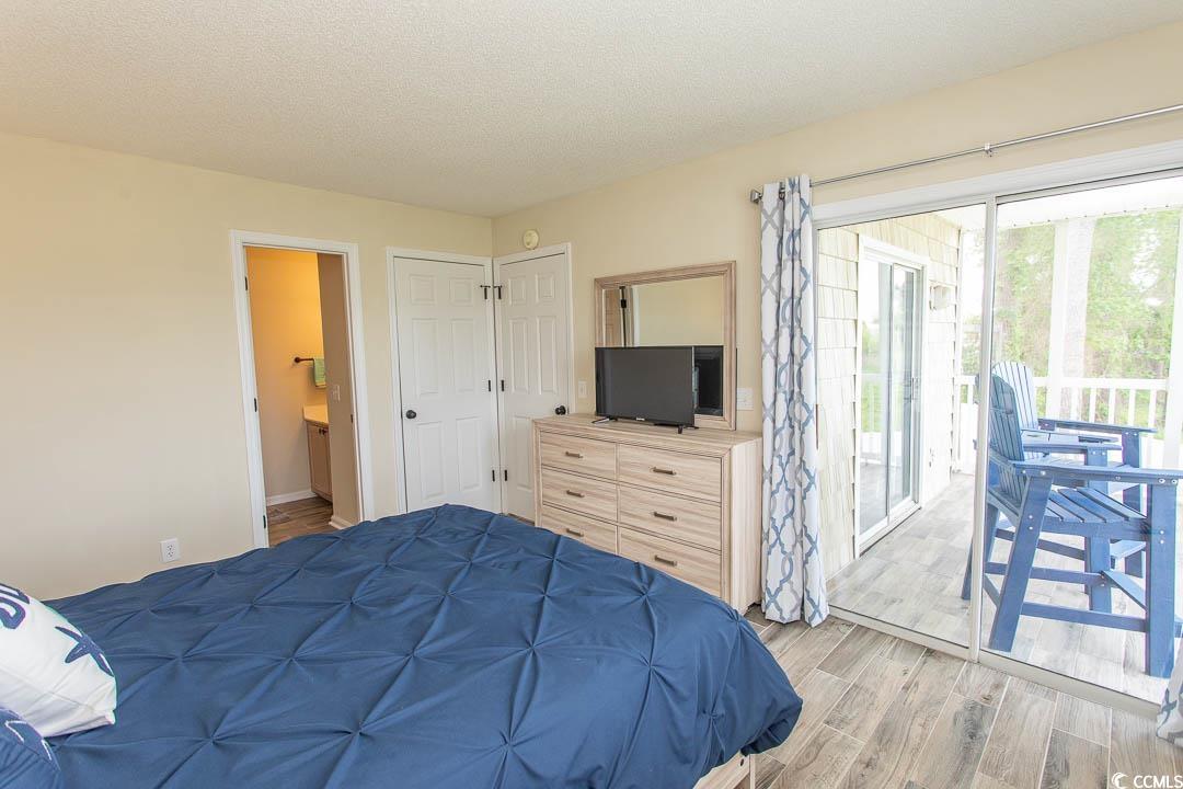 201 Landing Road, Unit D North Myrtle Beach, SC 29582 - Photo 17 of 40 Bedroom featuring a textured ceiling, connected bathroom, light wood-style flooring, baseboards, and access to exterior
