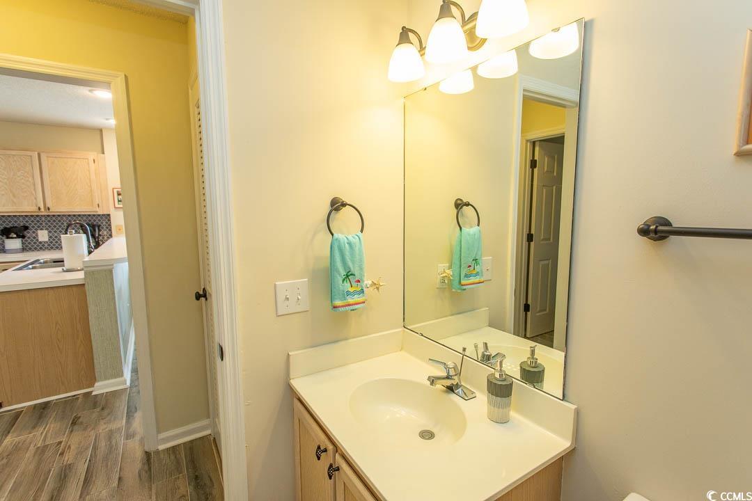 201 Landing Road, Unit D North Myrtle Beach, SC 29582 - Photo 27 of 40 Bathroom featuring wood finished floors, an inviting chandelier, vanity, and tasteful backsplash
