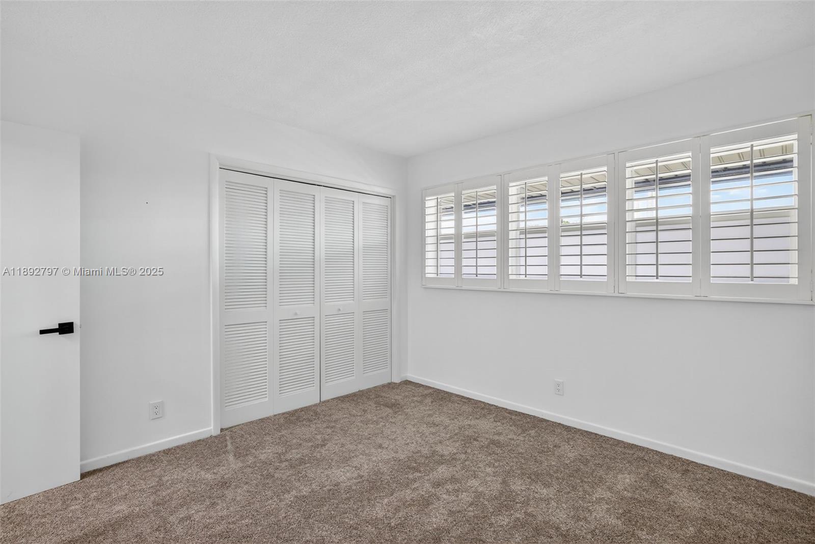 900 Southwest 12th Street, Unit 305 Fort Lauderdale, FL 33315 - Photo 41 of 72 Large guest bedroom w/ louvered shutters / impact windows, upgraded carpet and view to downtown from front windows