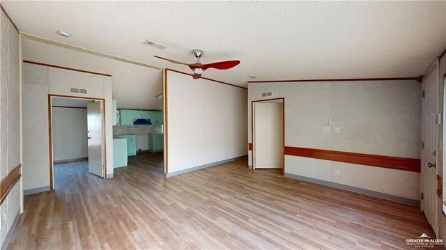 a view of an empty room with wooden floor and a cabinet