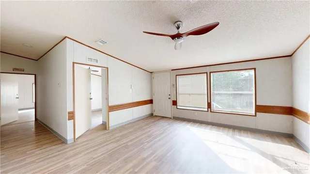 a view of an empty room with a window and wooden floor